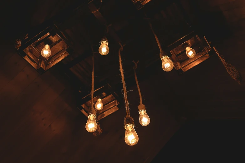 an array of hanging lighting with lit bulbs on dark ceiling