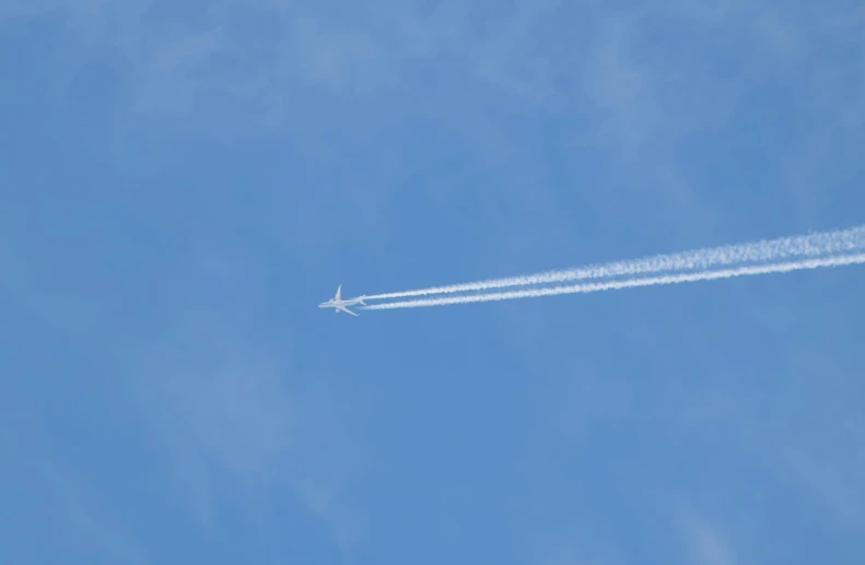 a plane flies in the air with a contrail