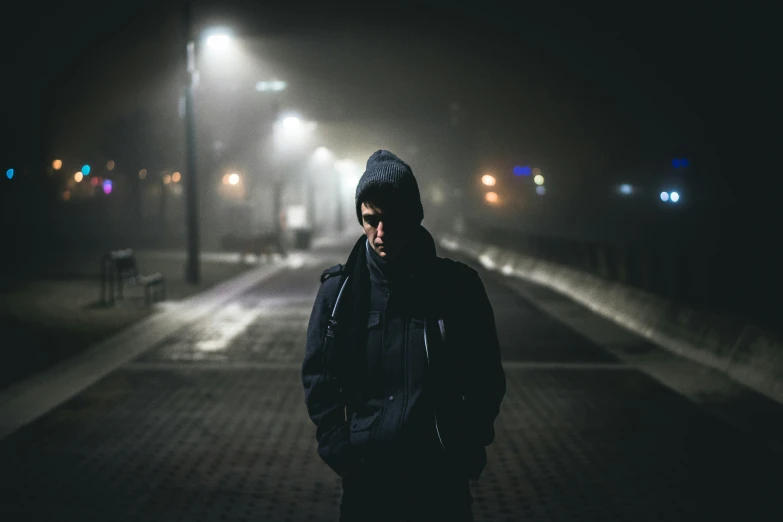 a man standing on the side walk with dark background