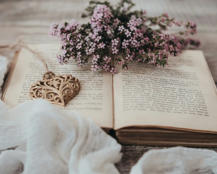 a book is sitting open next to a vase filled with flowers