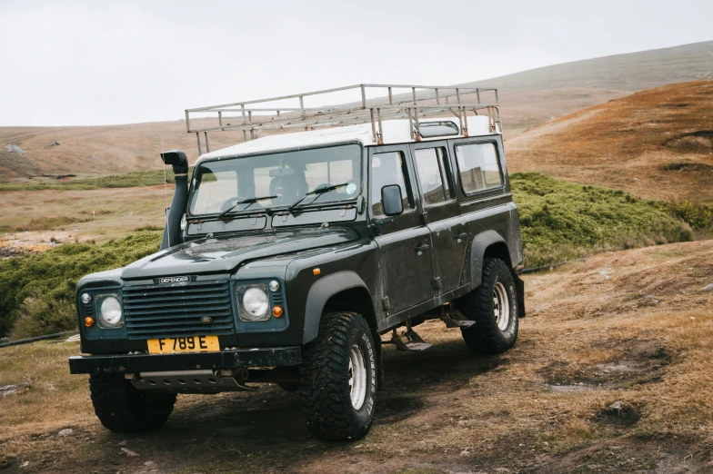 a defender suv parked on the side of a hill