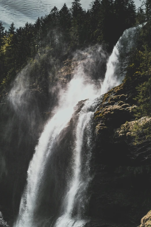 waterfall cascading near small rocky area of wooded area