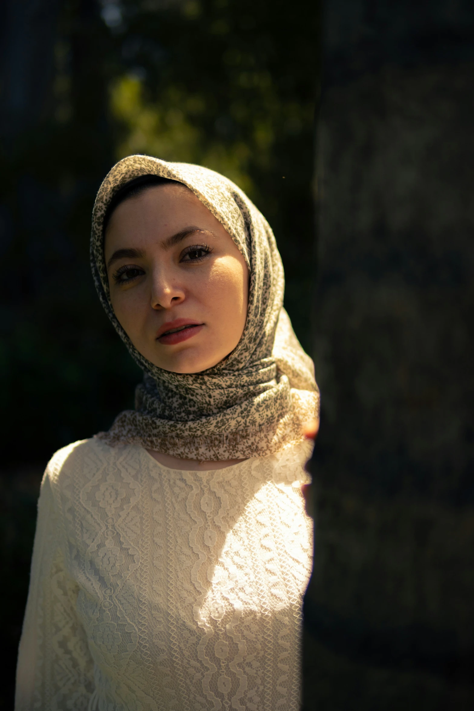 a woman in head scarf standing by trees