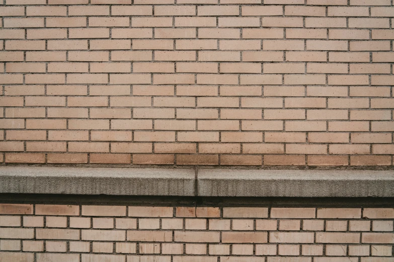 a brick wall and sidewalk with a stop sign attached to it