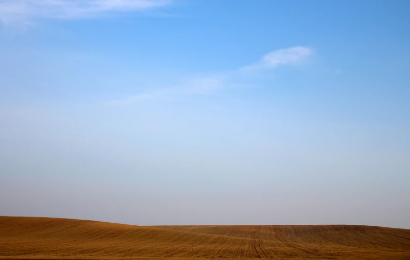 a large brown field with a sky in the background