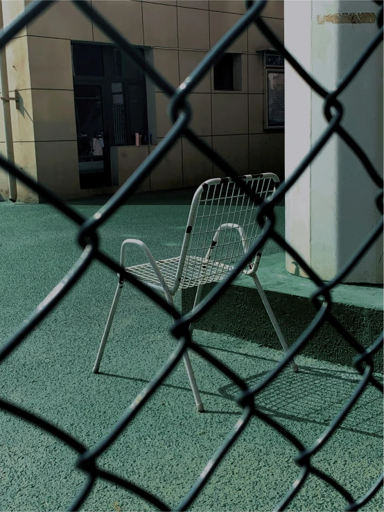 an empty metal chair near a chain link fence