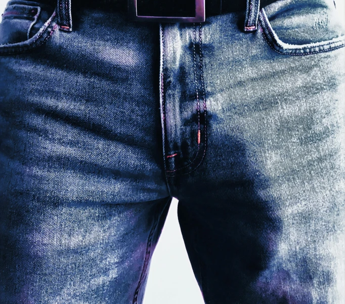 a person wearing blue jeans and a belt holding a cellphone