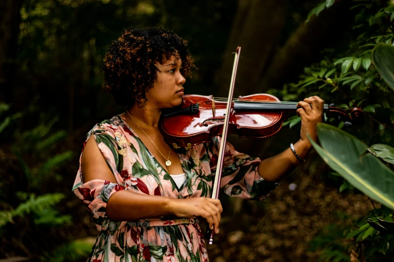 a woman standing outside while playing a violin