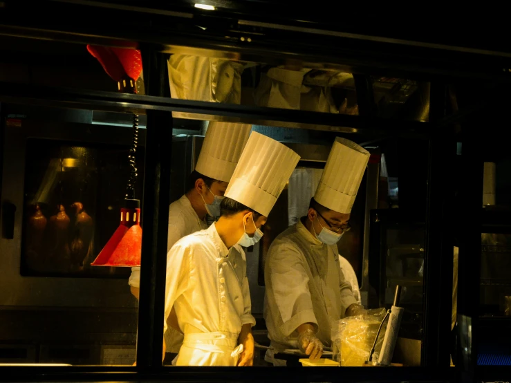 several chefs standing together preparing food on a dark street