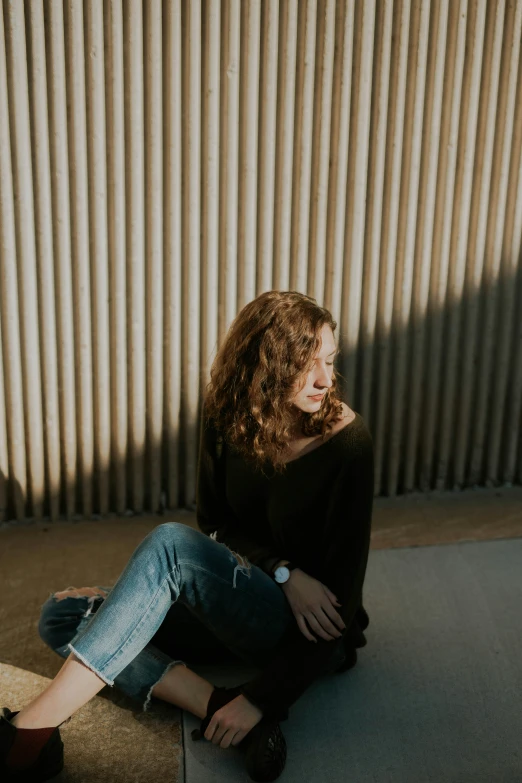 a woman with long hair sitting on the ground