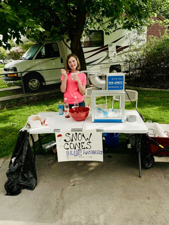 a young lady holding up an ice cream on a table