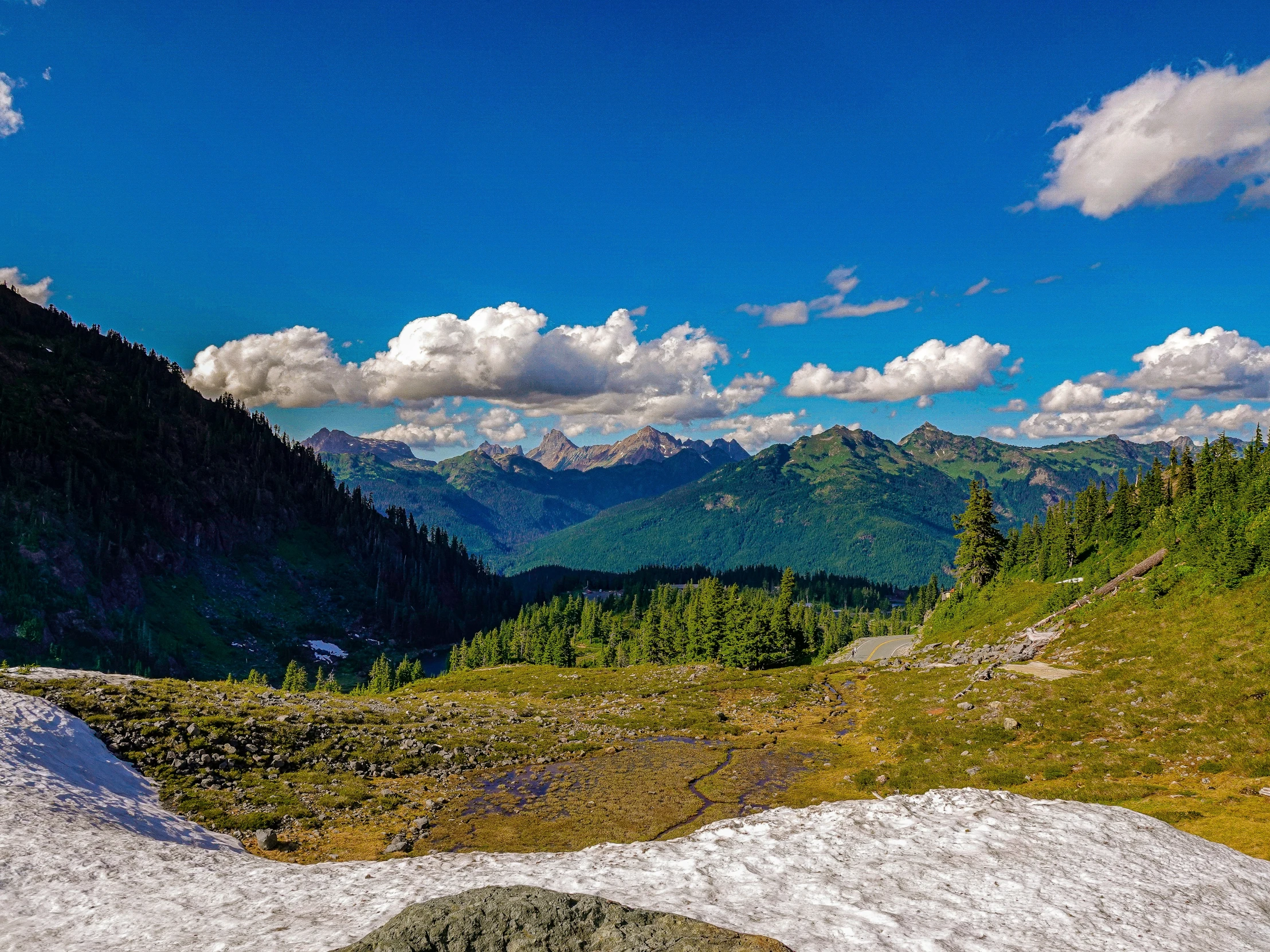 a bench overlooking mountains with a sky background