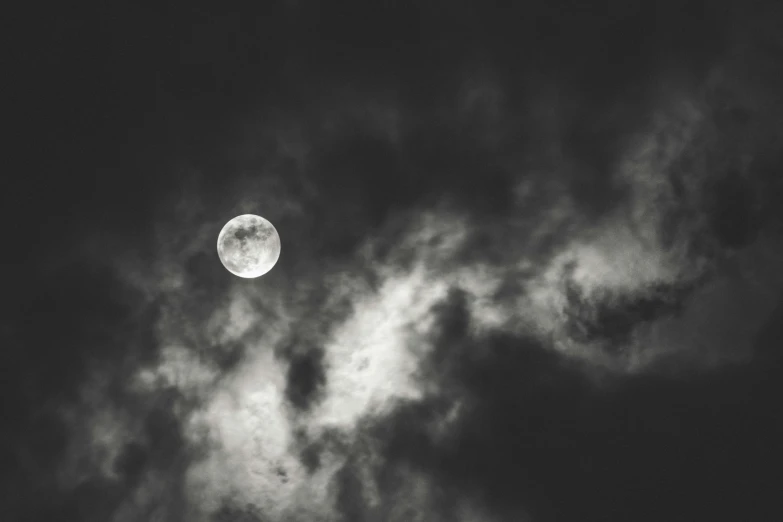 a full moon rises through the clouds in this black and white po