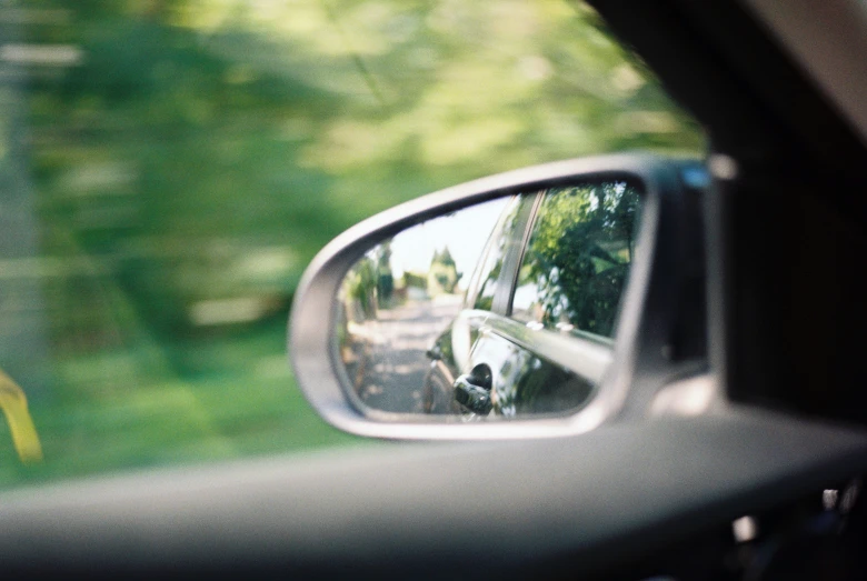 the reflection of a car parked on the road in the rear view mirror