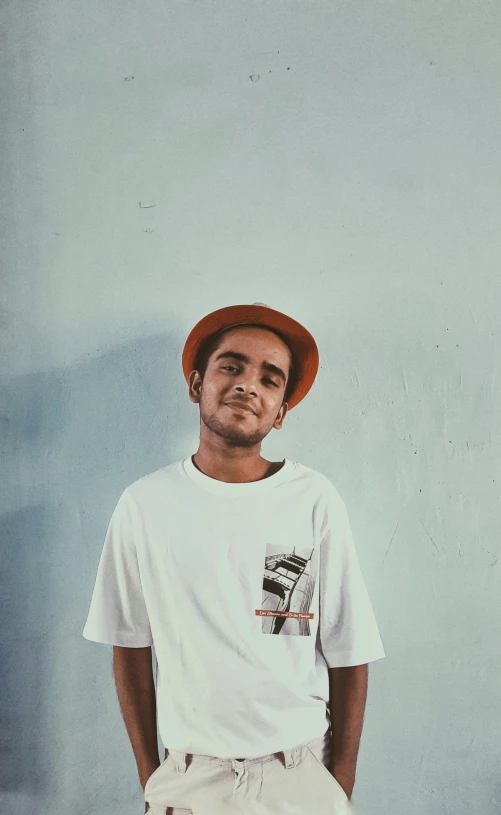 a man is standing near a blue wall with a skateboard