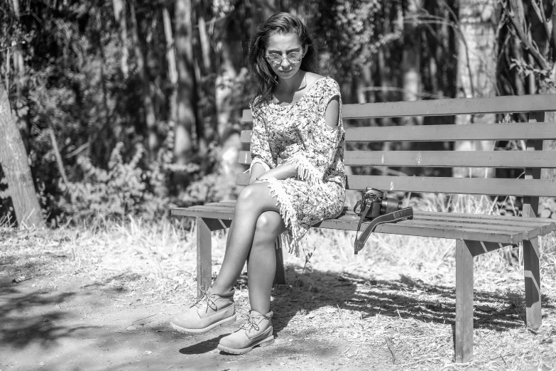 a woman in a dress sitting on a wooden bench