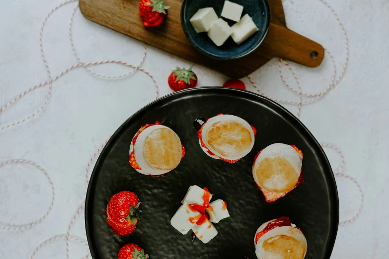 some strawberries and pieces of cake on a black plate