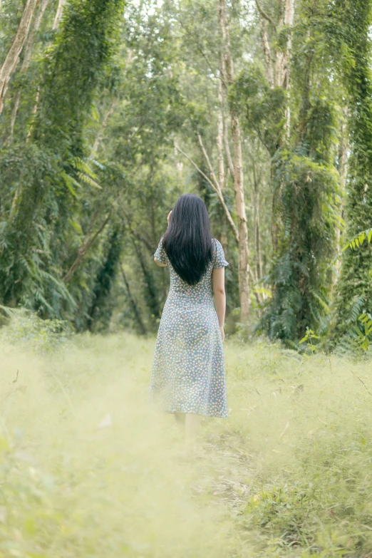 a woman wearing a dress standing in the grass in the woods