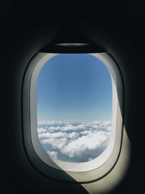 the inside view of a window showing clouds below