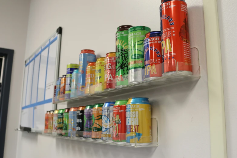 a variety of soft drink cans are lined up on two shelves