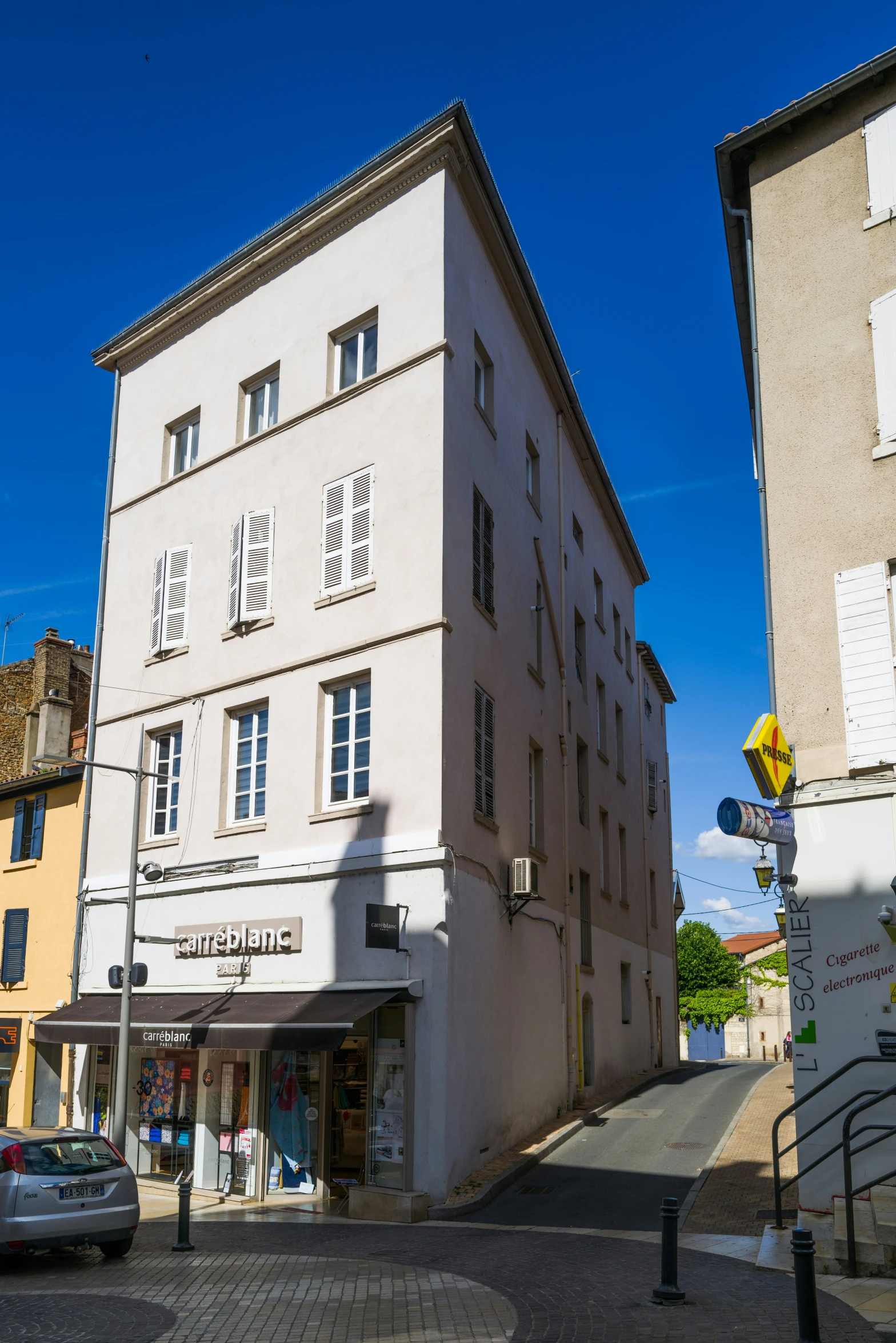 a large stone building on the corner in front of other buildings