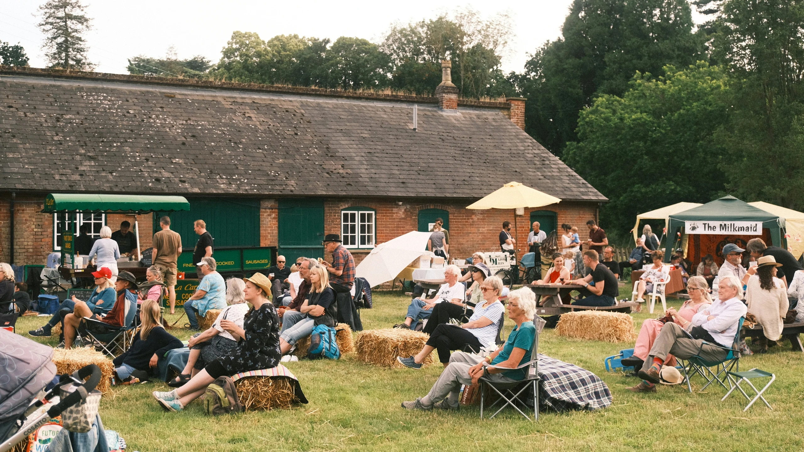 a field full of people sitting around in chairs and hay bales