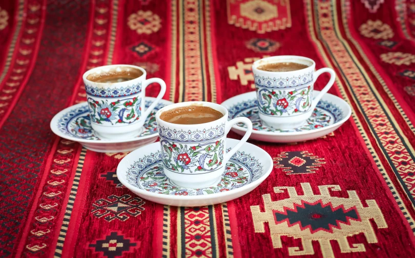 two cups of coffee on a tablecloth with an oriental design