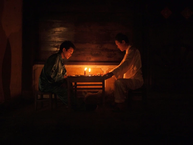 two men standing near a table with a lit candle in it