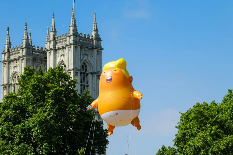 a big balloon floats high above a tree covered field