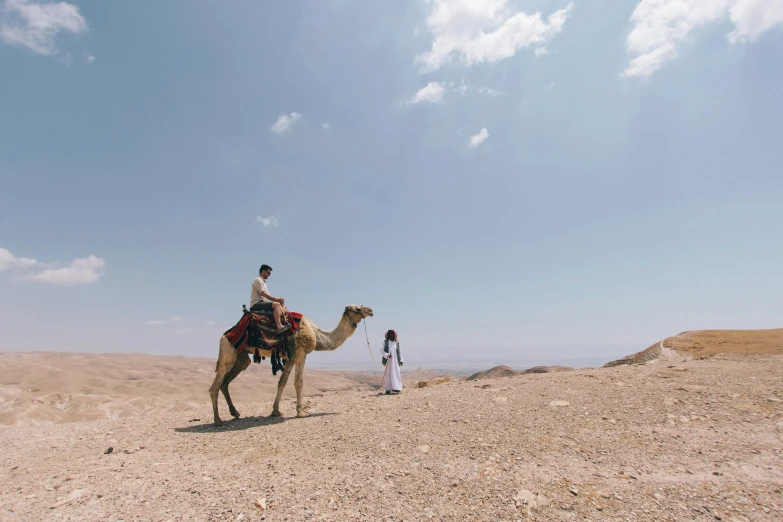 two people are sitting on top of a camel