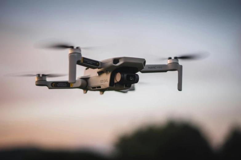 a remote controlled device in the air against a backdrop of trees