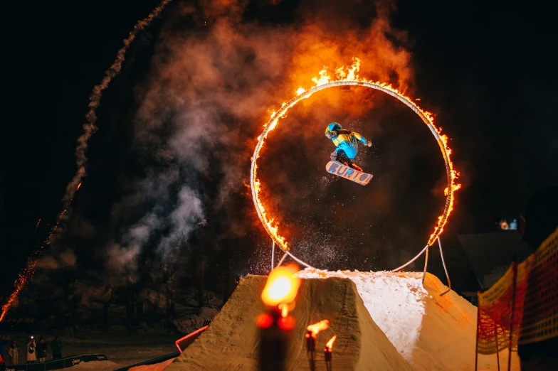 a skier is performing an aerial trick on the fire hoop