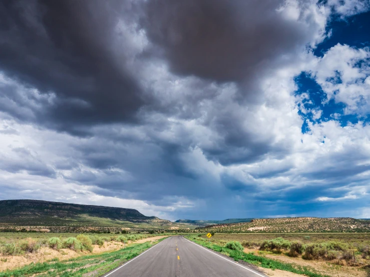 a stormy cloud is hovering over an asphalt road