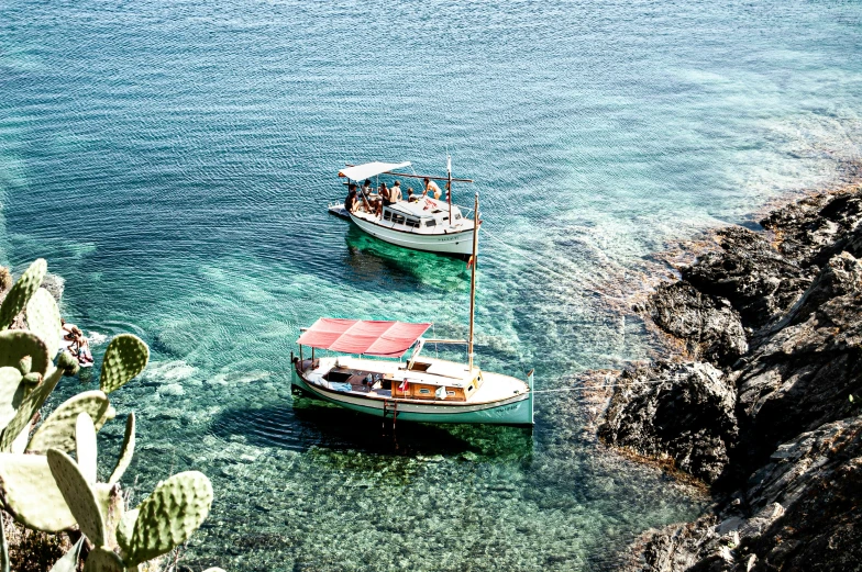 two small boats in a body of water near a rocky shoreline