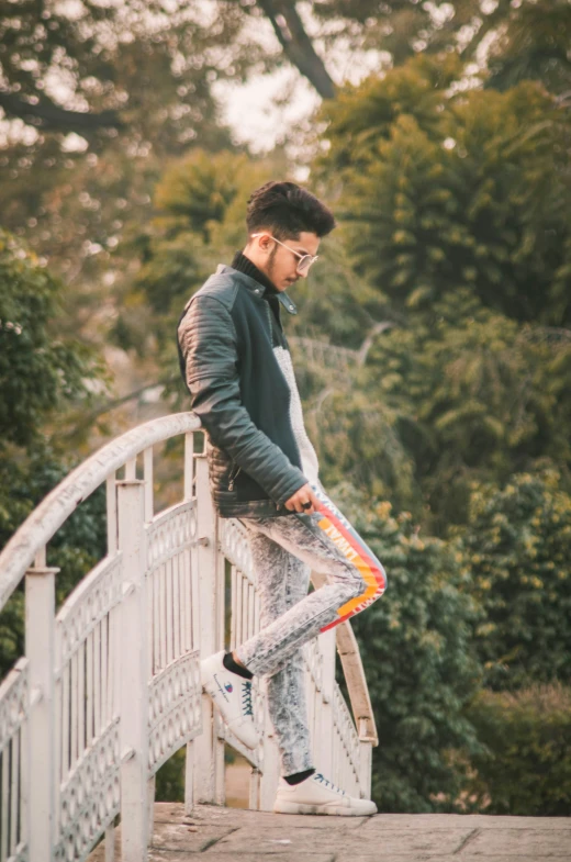 man standing on bridge with skateboard near him