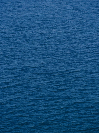 a lonely boat floating on top of blue water