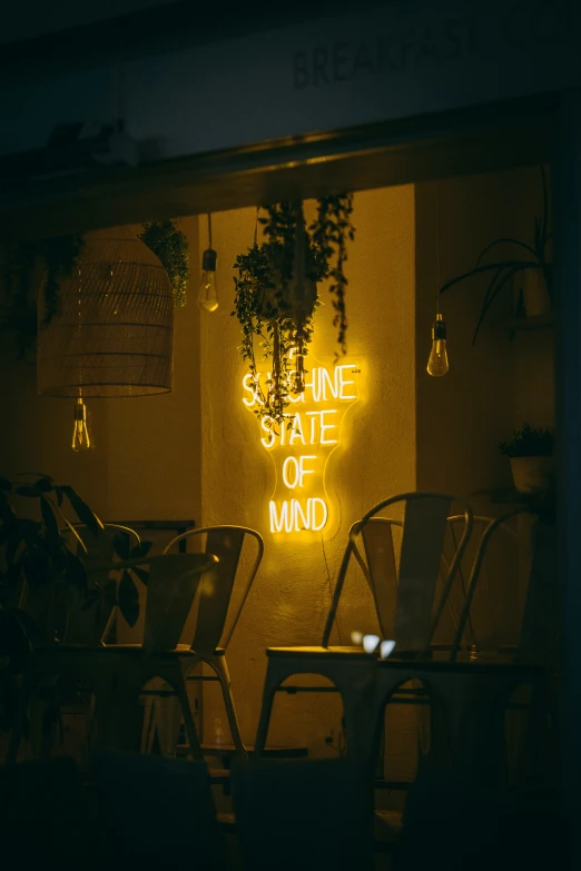 a neon sign sitting above chairs in a room