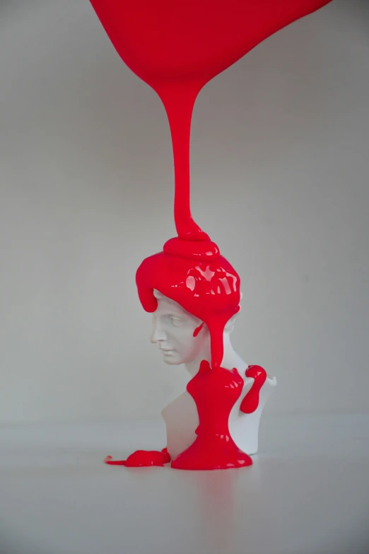 a bottle dripping with red liquid on top of a white head