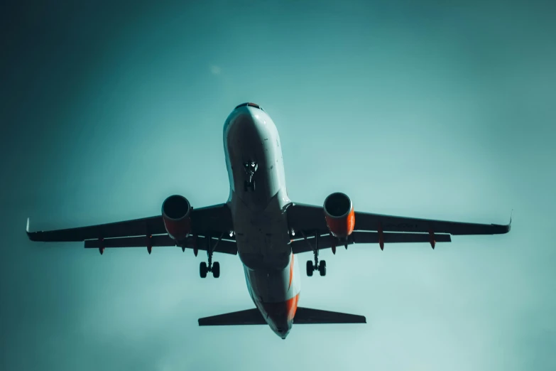 a commercial airliner with its landing gear down and its front engine extended, is flying through the sky