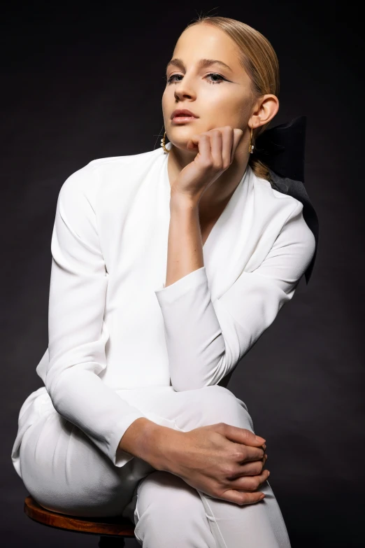 a woman sitting in a chair wearing white clothing