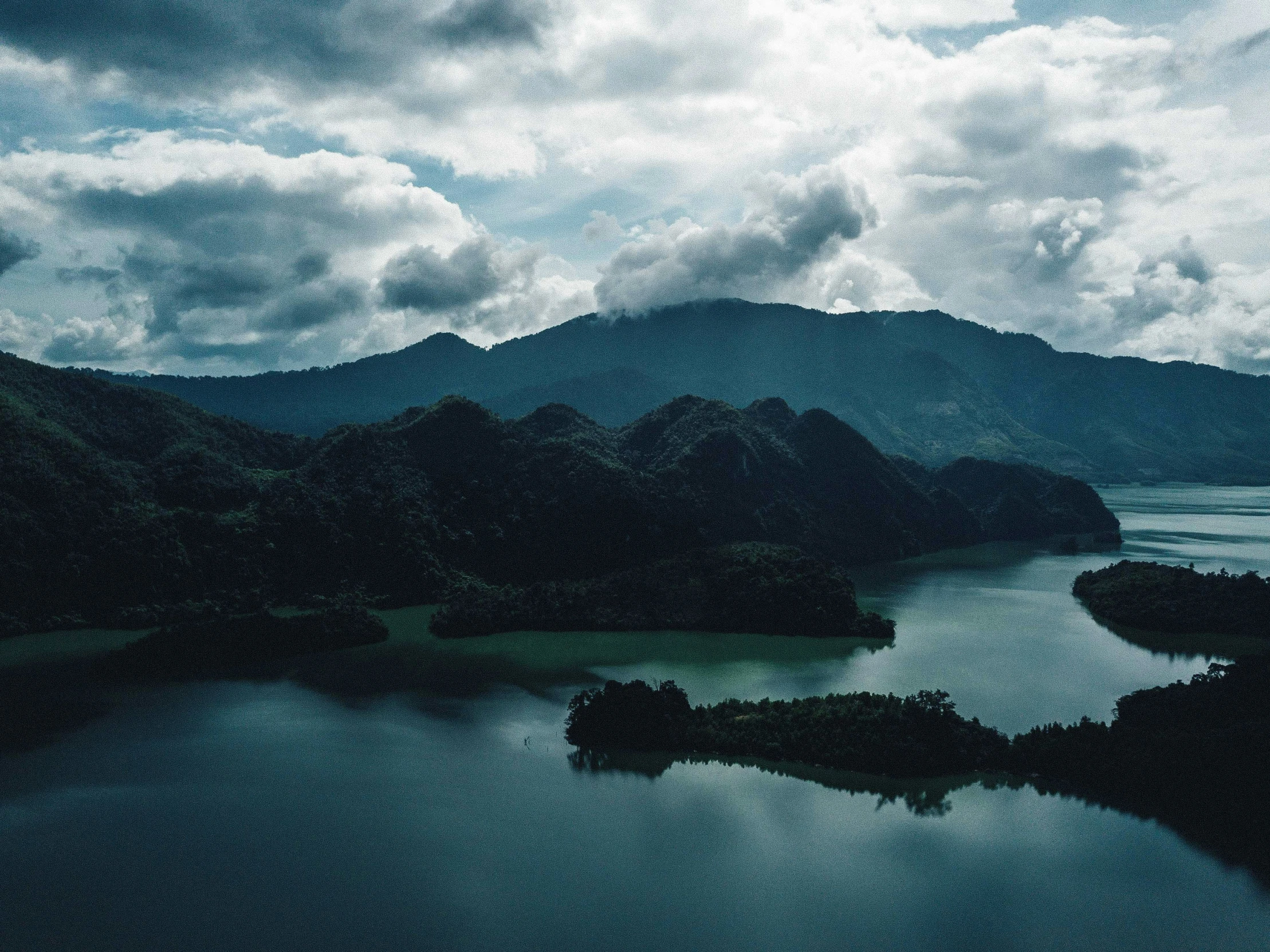 an island sits in a lake surrounded by green mountains