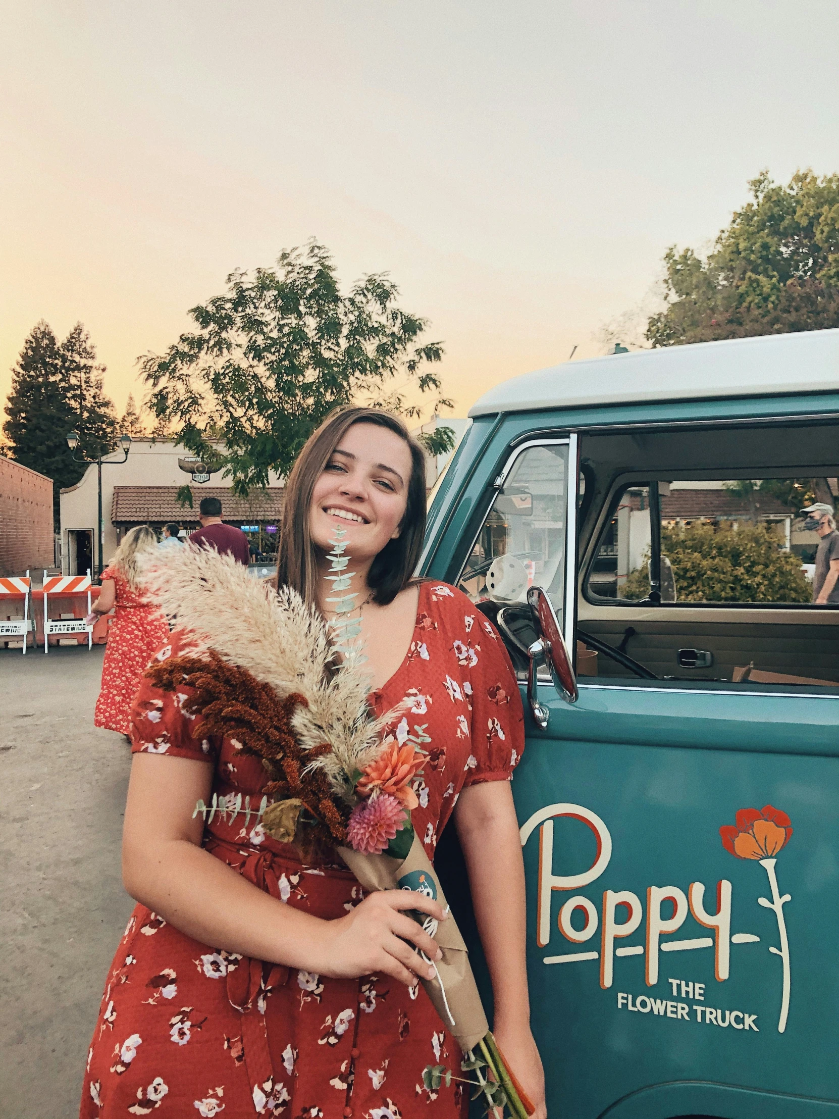 a woman posing with flowers by her camper