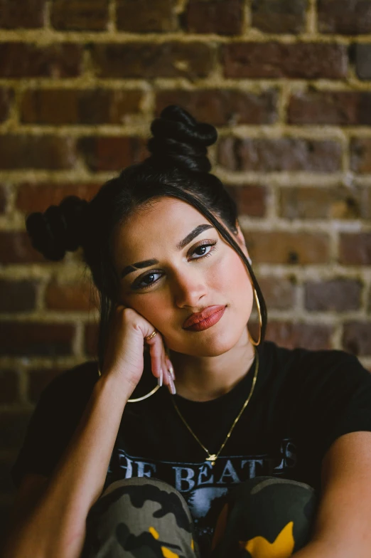 a woman is sitting in front of a brick wall