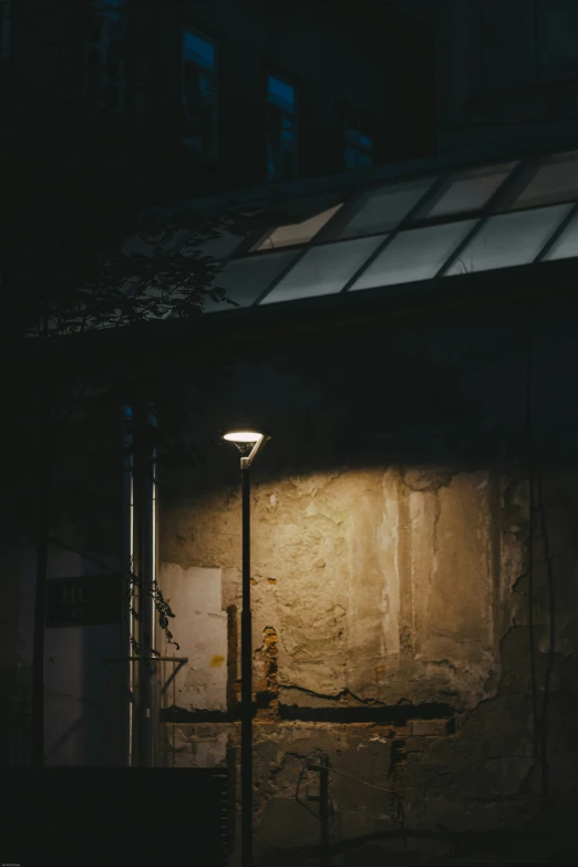 the back wall of an old abandoned building with a street light shining in the dark