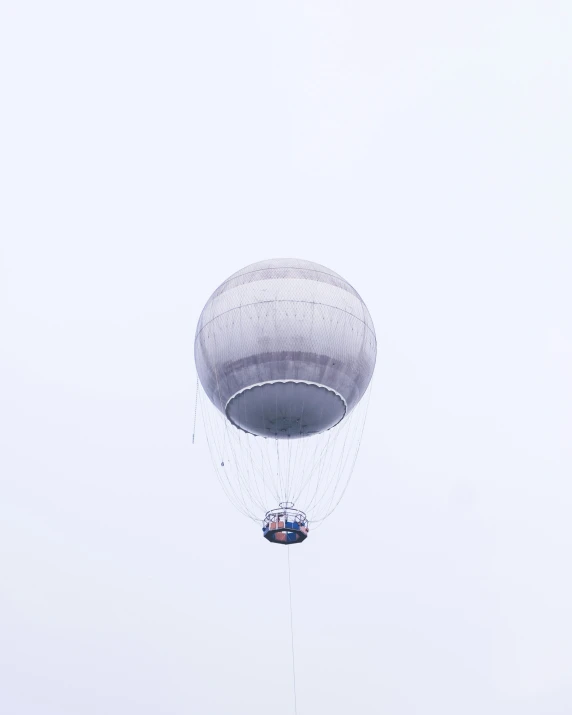 a gray balloon with two people inside in the sky