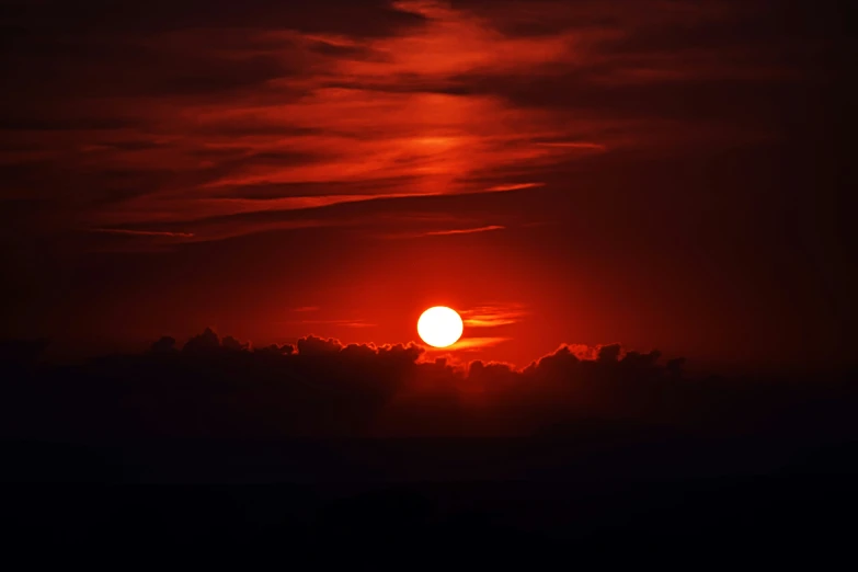 the sun is setting with dark clouds in the sky