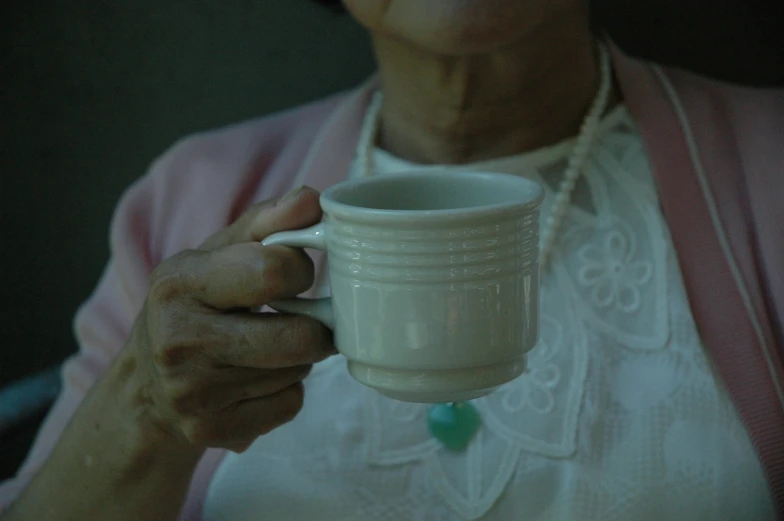 an older lady holding a cup in her hands