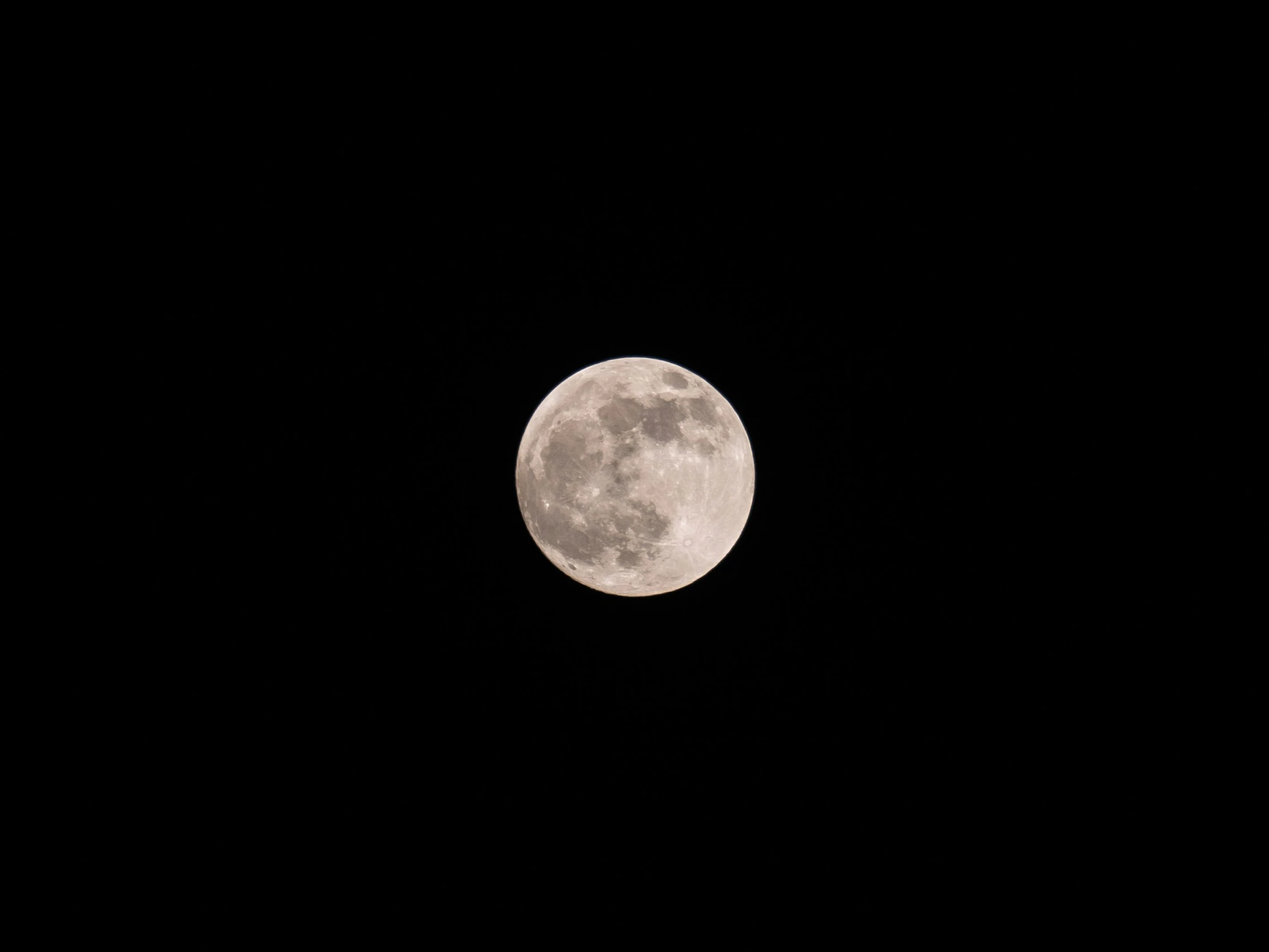 full moon seen from a distance with dark sky