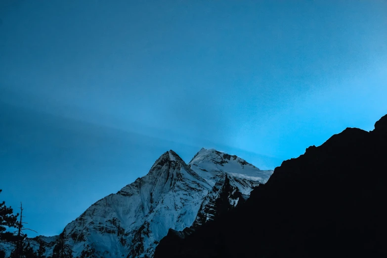 a snowy mountain with trees on it at night