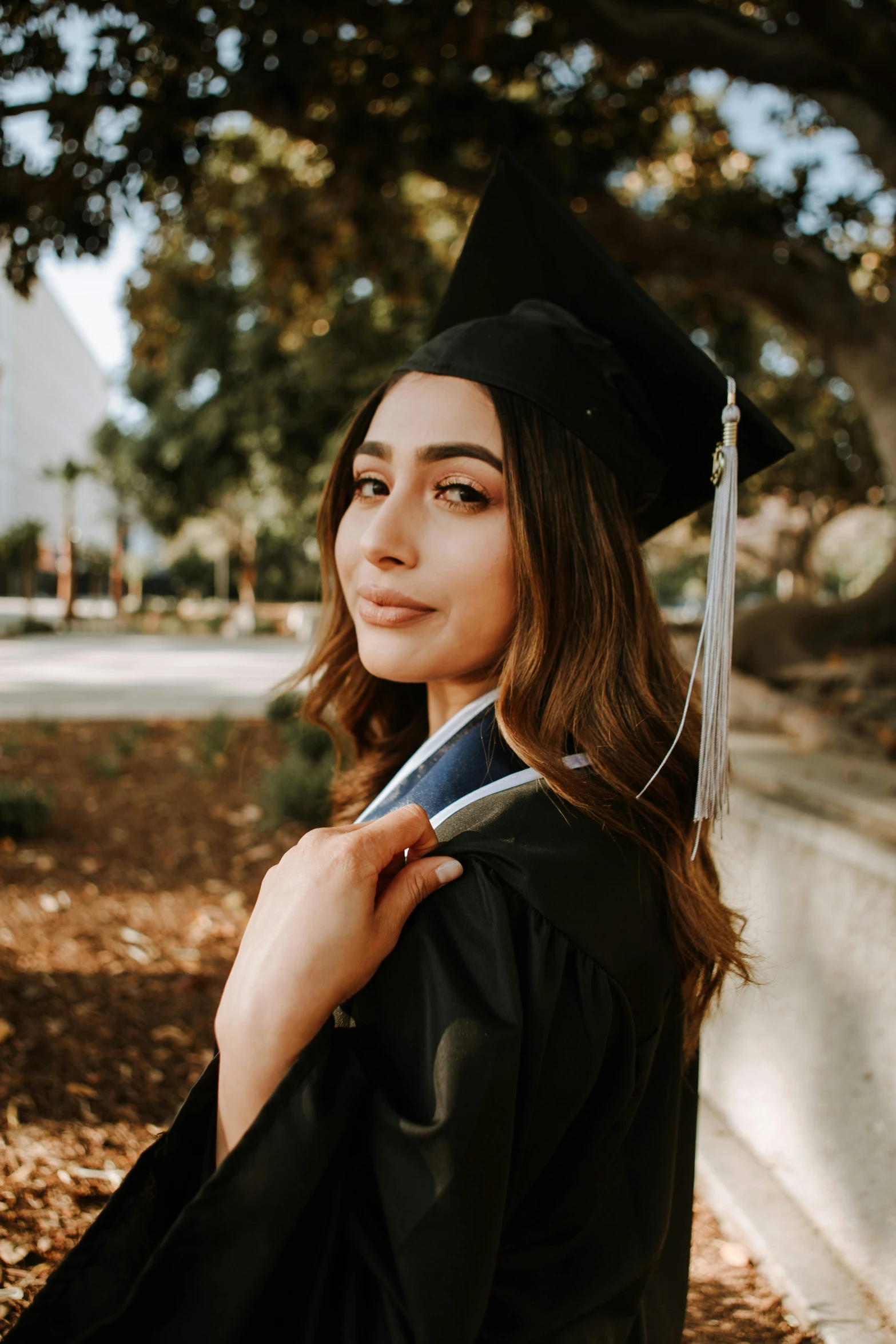 a young woman in graduation clothes holding a graduate cap